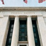 American flags waving around the entrance to the Federal Reserve building.
